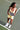 Woman in yellow sports bra and shorts holding a checkered paddle on a tennis court